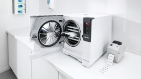 Ein geöffneter Cube Sterilisator auf einer Aufbereitungszeile mit Etikettendrucker.